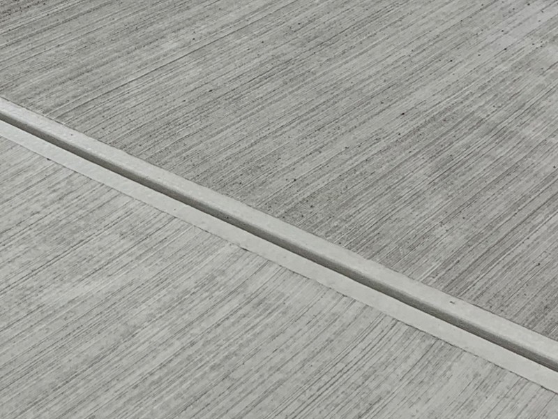 Close-up of parallel broom grooves in gray concrete